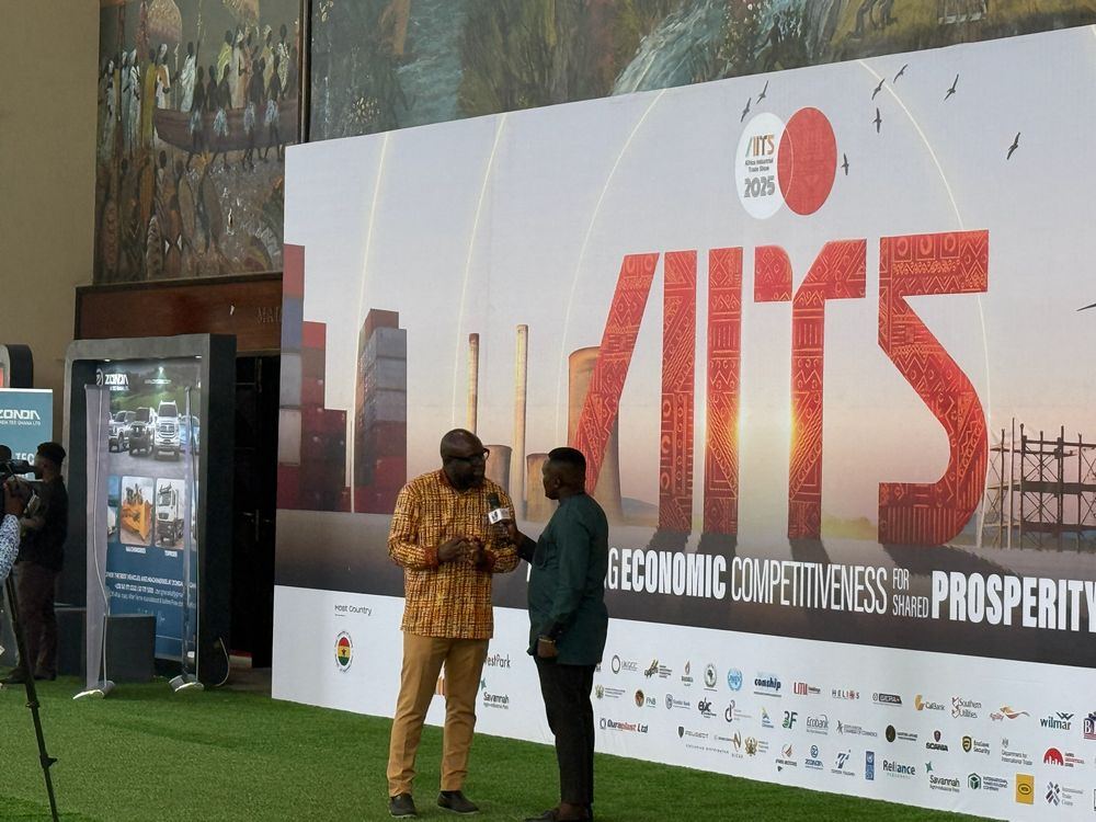A media interview takes place at the AITS 2025 backdrop
