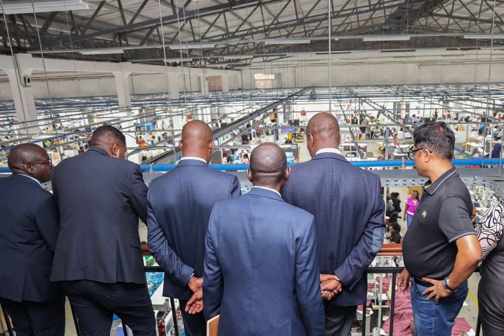 Delegation overlooking a manufacturing facility floor